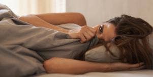 shy woman in bed with blankets covering her
