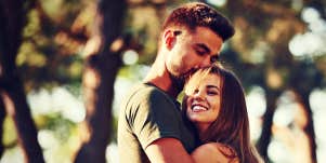 brunette couple ein woods, he kisses her head, she smiles