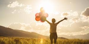 hopeful woman holding balloons while watching the sun