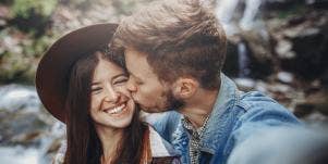 man kissing a smiling woman on the cheek
