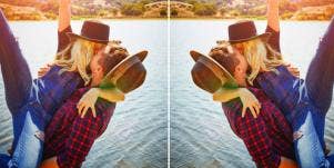 couple wearing plaid and hats kissing by the water