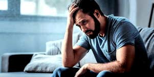 emotionally unstable man sitting with his head in his hand