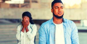 woman holding her head in her hands behind man who is over her