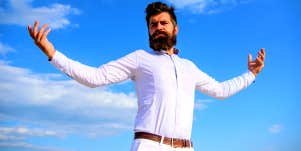 bearded man standing in front of clouds