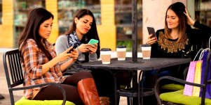 group of friends sitting at a table looking at their phones instead of talking to each other