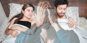 Man checking under covers in bed with woman