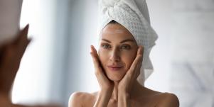 woman looking in mirror with towel on her head