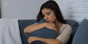 woman looking sad, holding couch pillow