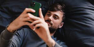 man laying in bed looking at phone