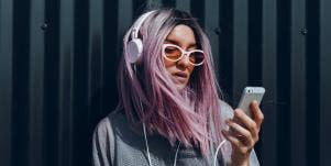 woman with purple hair listening to music on her phone