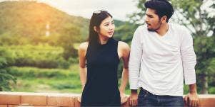 woman and man leaning against fence post
