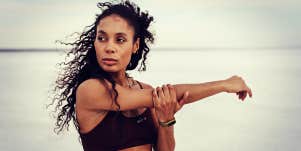 Black woman athlete stretching and looking very serious outdoors