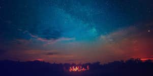campers under the night sky with a shooting star