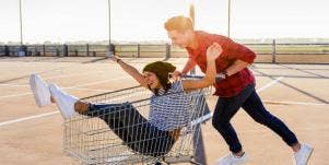 man pushing woman in shopping cart