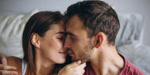 man and woman kissing in bed