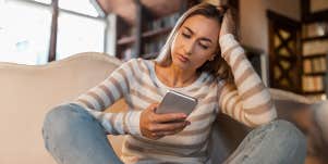 woman looking at iphone with head in hand