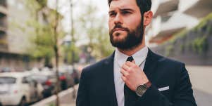 successful man in suit adjusting tie