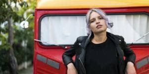 superficial person leaning against a car