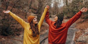 two friends with their arms up having fun outdoors