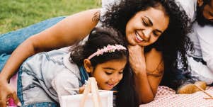 mom and daughter look at her art on picnic blanket 