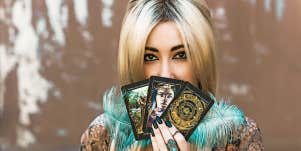 Woman peeking over three tarot cards.