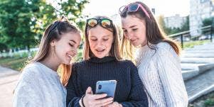 three teenage girls looking at a smartphone
