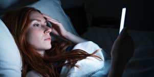 woman looking at phone in bed