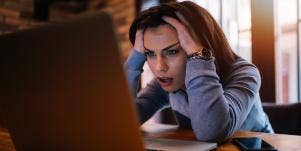 woman with her head in her hands looking at computer screen