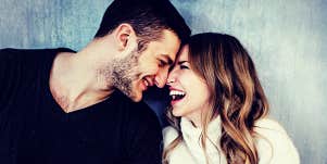 man and woman laugh together, foreheads touching