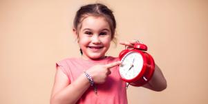 little girl pointing at a red clock