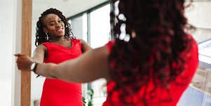 confident woman in red dress looking in mirror