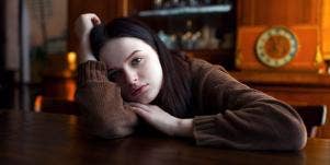 glum-looking woman with her head on the table