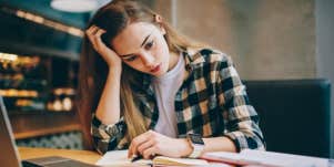 Woman in plaid shirt at desk looks depressed about work