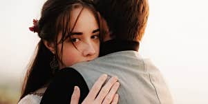 Couple hugging, woman looking over the man's shoulder 