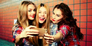 three girls taking a selfie in a bathroom