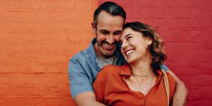 couple cuddling in front of an orange and red wall