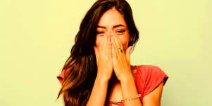 embarrassed woman laughing covering mouth