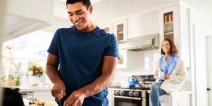 Woman convincing man to cut food while she watches