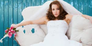 bride sitting on couch in front of blue background looking worn out