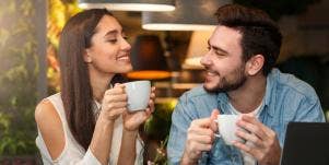man and woman smiling at each other over coffee