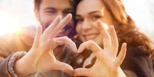 couple making a heart with their fingers