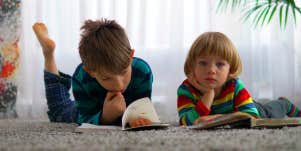 two children laying on the floor reading books