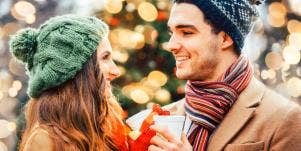 man and woman in winter hats toasting cups