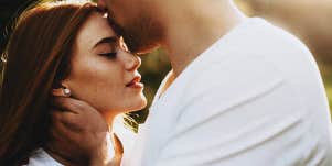 man kissing woman's forehead