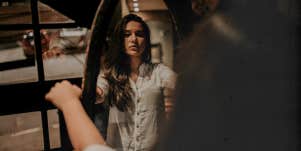 Woman grasping the sides of the mirror, looking at herself