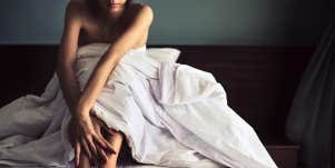 woman sitting in bed under covers