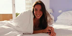 smiling woman in bed under covers