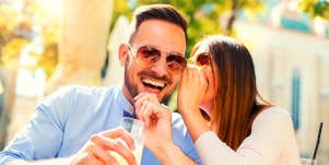 woman whispering emotional trigger phrases into a smiling man's ear