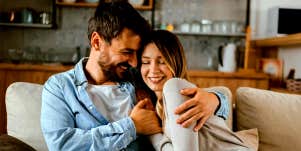 husband and wife sitting on couch hugging and smiling