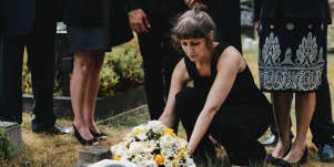 woman putting flowers on grave
